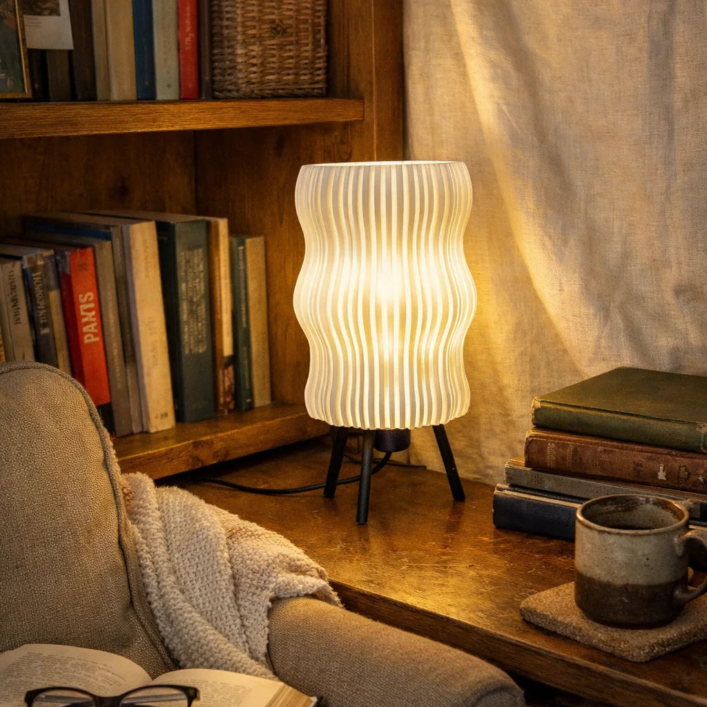 Cozy reading nook with a lamp, books, and a mug on a wooden table.